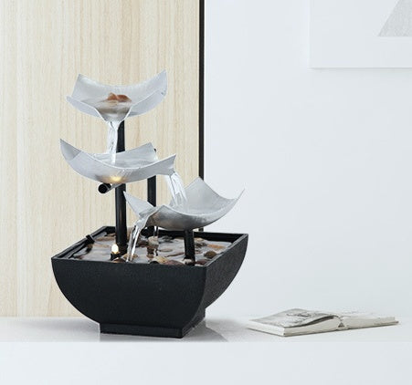 Decorative indoor water fountain with black base and white bowls on a light background