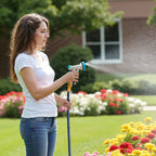 Woman watering garden flowers with adjustable spray hose nozzle in backyard
