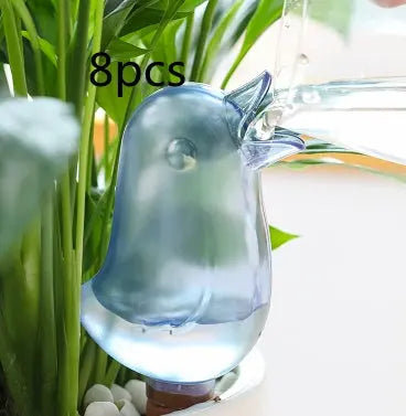 Blue bird-shaped plant watering globe in potted indoor greenery, water being poured in